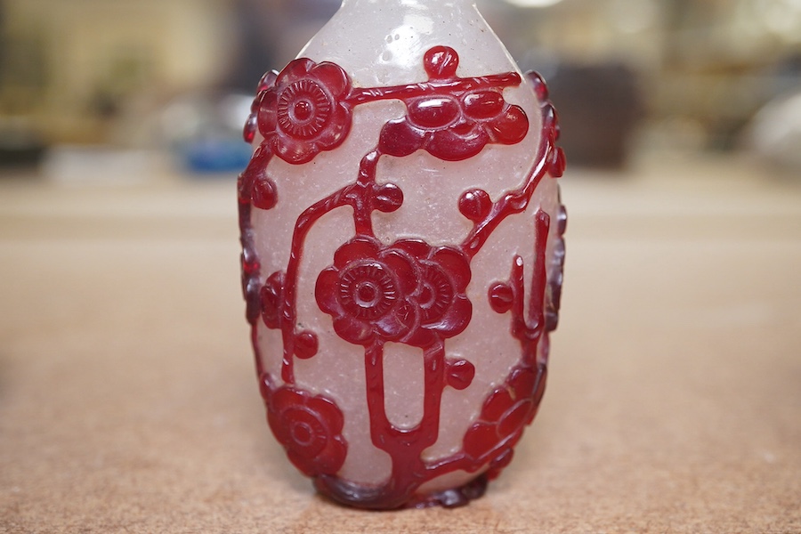 A Chinese cameo carved red overlaid on white snowflake ground snuff bottle and stopper, 19th century, 8cm high. Condition - small splinter chip to base, otherwise good